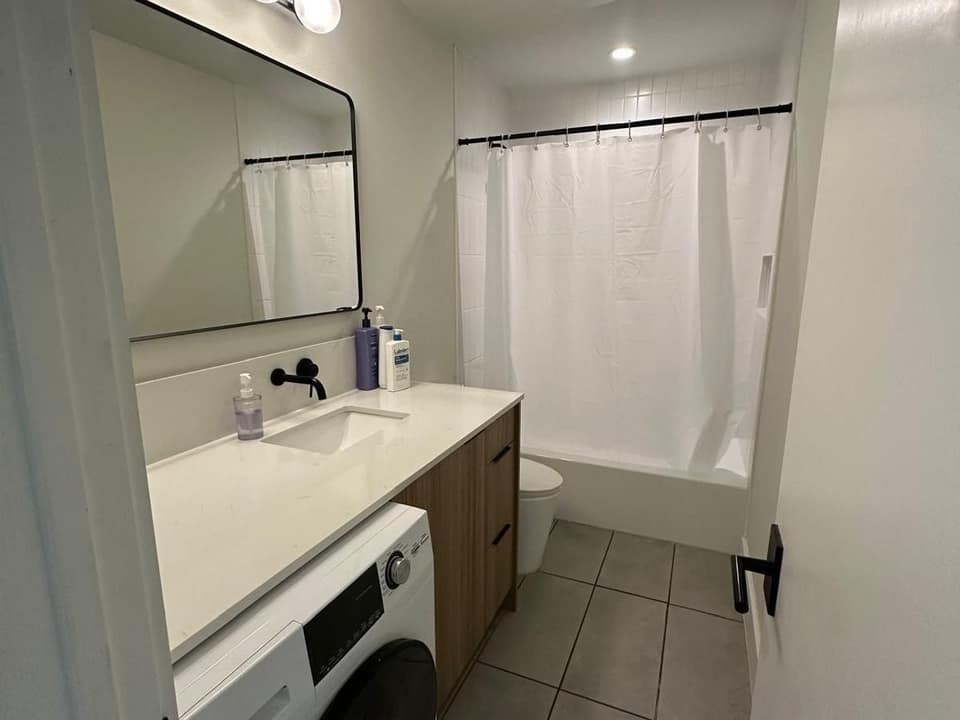 Spotless white bathroom with a clean vanity, mirror, shower and tiled floor