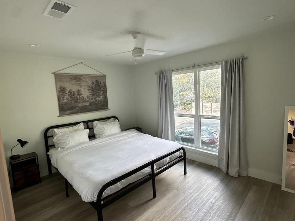Nearly empty bedroom with bare walls, a made bed and clean floors, ready to show