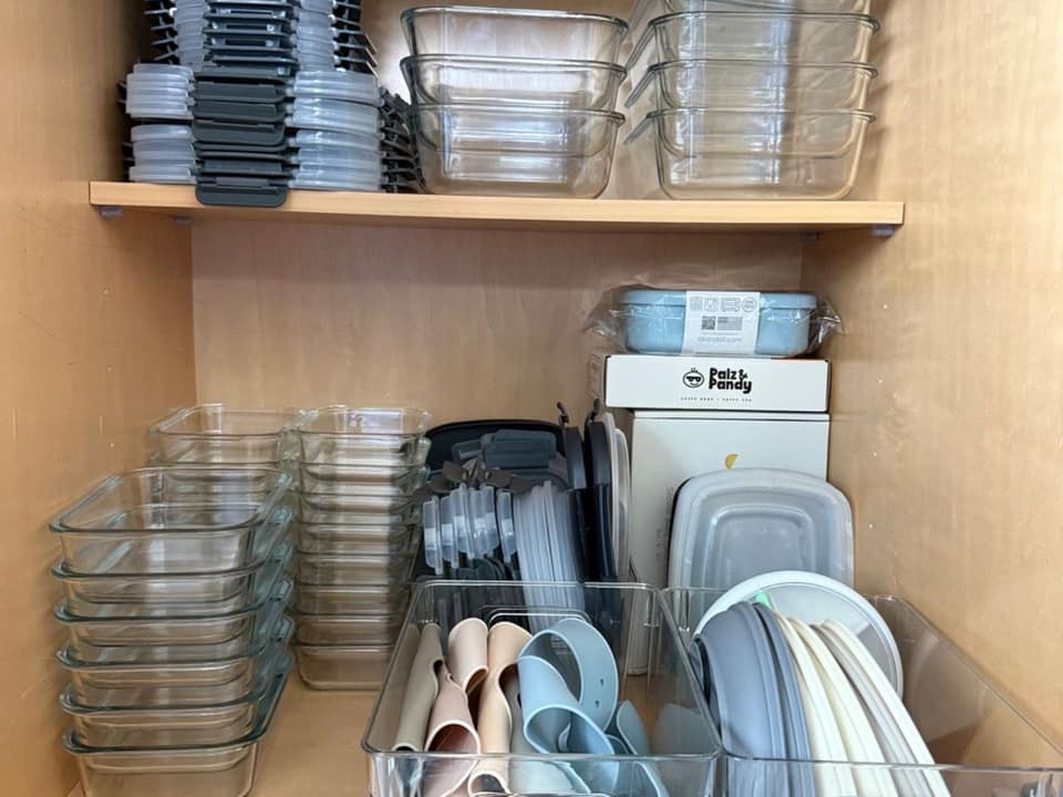 Kitchen cabinet after organizing, with glass containers and lids sorted and stacked in rows