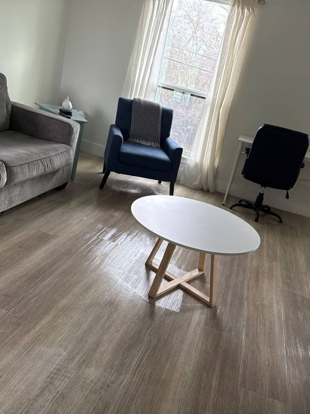 Clean living room with a sofa, armchair and coffee table on wiped wood floors