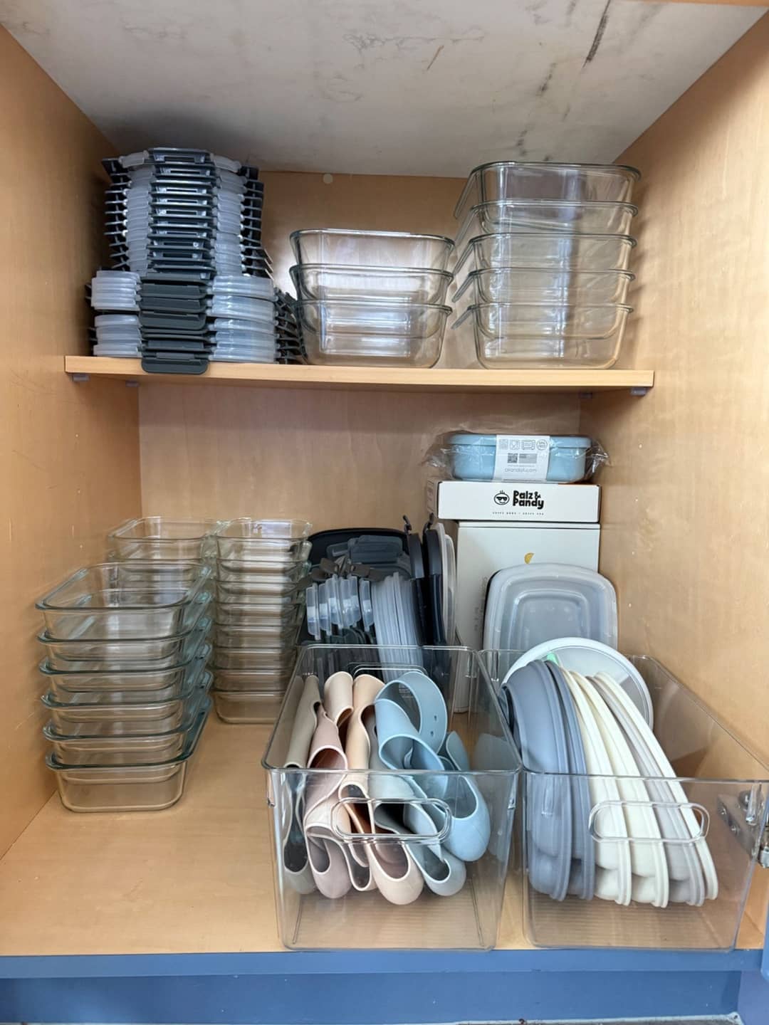 Kitchen cabinet after organizing, with glass containers and lids sorted and stacked in rows
